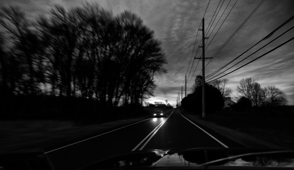 black and white photo of a car with headlights on